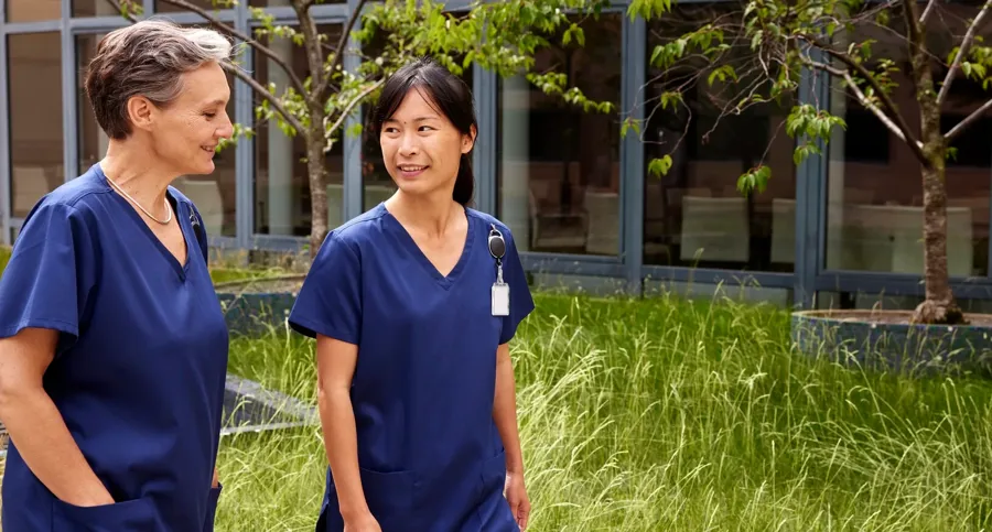 Image of two healthcare professionals outside. Coloplast offers both high- and low-volume TAI options.    