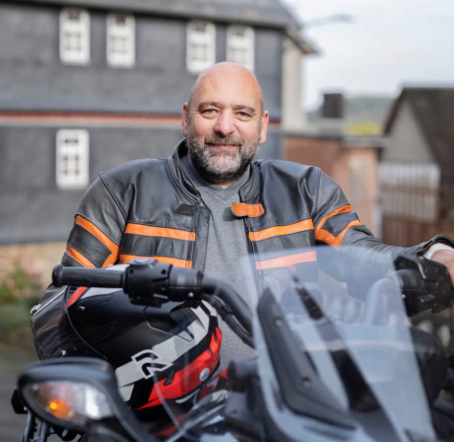 Portrait photo of Michael sitting on his motorbike. 